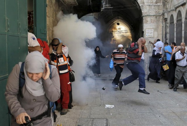 Người biểu tình Palestine bỏ chạy khi cảnh sát Israel ném lựu đạn hơi cay tại thành phố Jerusalem.