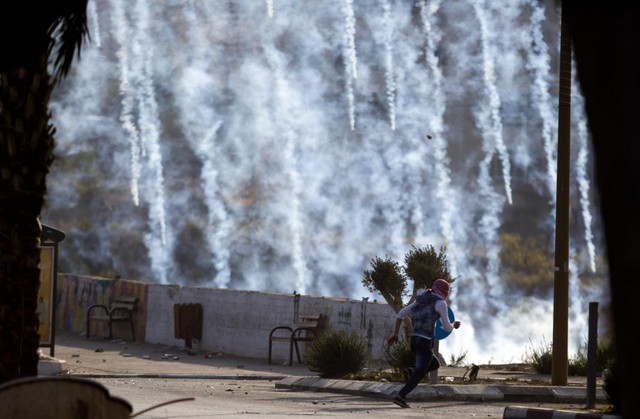 Người biểu tình Palestine chạy tìm nơi ẩn nấp sau khi bị binh sĩ Israel bắn đạn hơi cay tại thành phố Ramallah, Bờ Tây.