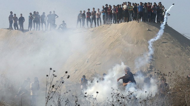Người biểu tình Palestine ném lựu đạn hơi cay trả lại phía binh sĩ Israel trong cuộc đụng độ tại thành phố Gaza, Bờ Tây.