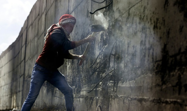 Người biểu tình Palestine sử dụng búa để đập thủng bức tường bê tông ngăn cách thành phố Abu Dis và Jerusalem ở Bờ Tây.