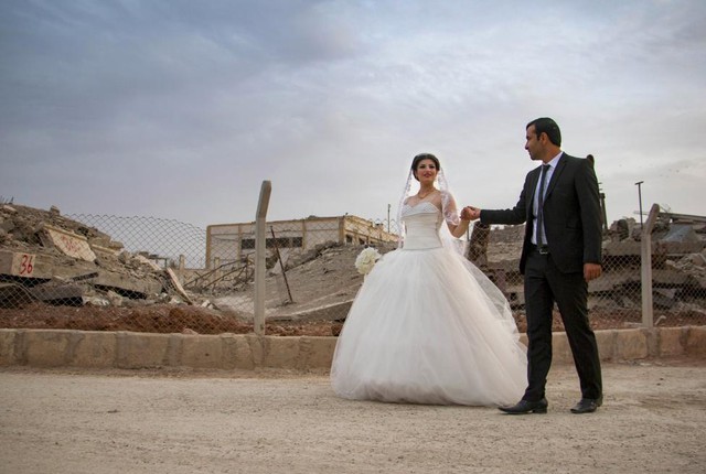 Cặp đôi nắm tay nhau đi qua những tòa nhà đổ nát trong lễ cưới của họ tại thị trấn Kobani, Syria.