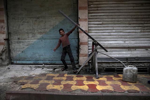 Cậu bé đang bơm nước vào can từ một giếng khoan tại thị trấn Douma, Syria.