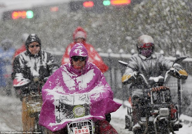 Người dân vất vả di chuyển bằng mô tô dưới mưa tuyết ở thành phố Bắc Kinh, Trung Quốc.