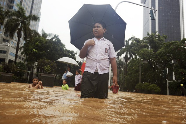 Một cậu bé lội qua nước lũ ở Jakarta, Indonesia. Mưa và triều cường trong những ngày gần đây đã gây ra lũ lụt trên diện rộng ở khắp Indonesia.