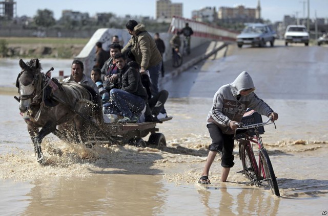 Người dân Palestine vượt qua đoạn đường ngập lụt tại ngôi làng Bedouin ở Dải Gaza.