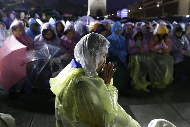 Người phụ nữ cầu nguyện dưới mưa ở Seoul, Hàn Quốc, trong lễ kỷ niệm 1 năm xảy ra thảm hỏa đắm phà Sewol, khiến hơn 300 người thiệt mạng.