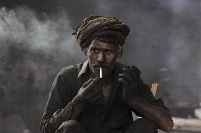 Công nhân nghỉ giải lao trong khi làm việc tại xưởng nung thép ở Lahore, Pakistan.