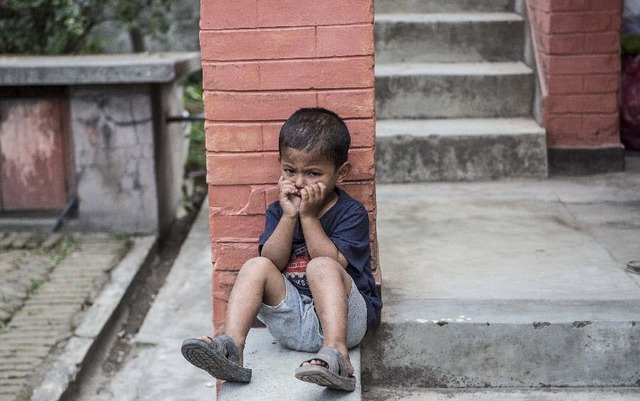 Cậu bé mồ côi ngôi chơi một mình trong trung tâm phân phát thực phẩm ở Kathmandu, Nepal.