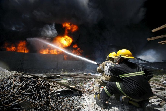 Lính cứu hỏa nỗ lực dập tắt đám cháy bùng phát tại một nhà máy sản xuất giày dép cao su ở thành phố Valenzuela, ngoại ô Manila, Philippines.