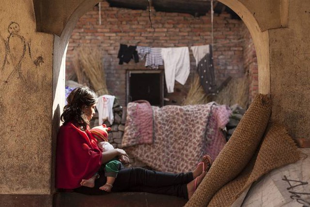 Người phụ nữ trẻ ôm con nhỏ tại khu trú ẩn tạm ở Kritipur, ngoại ô Kathmandu khi đất nước Nepal đang cố gắng khôi phục lại cuộc sống cho người dân sau 2 trận động đất kinh hoàng.