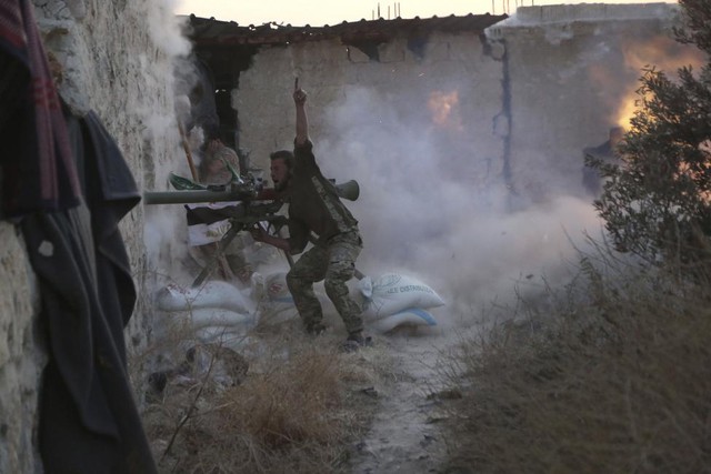 Một chiến binh phiến quân Syria báo hiệu khi nã đạn nhằm vào quân đội chính phủ ở thành phố Aleppo.