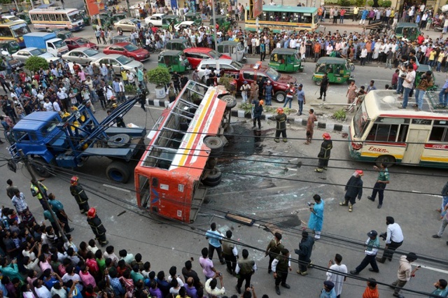 Người dân hiếu kỳ đứng quan sát tại hiện trường một vụ tai nạn xe bus ở Dhaka, Bangladesh, khiến 1 người chết và 15 người bị thương.