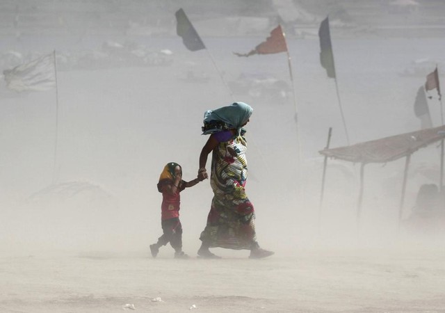 Bé gái nhắm mắt khi cùng mẹ đi trong bão cát trên bờ sông Hằng ở Allahabad, Ấn Độ.