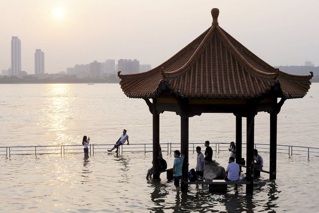Du khách chụp ảnh gần một thủy tạ bị ngập trong nước trên sông Dương Tử ở Vũ Hán, Trung Quốc.