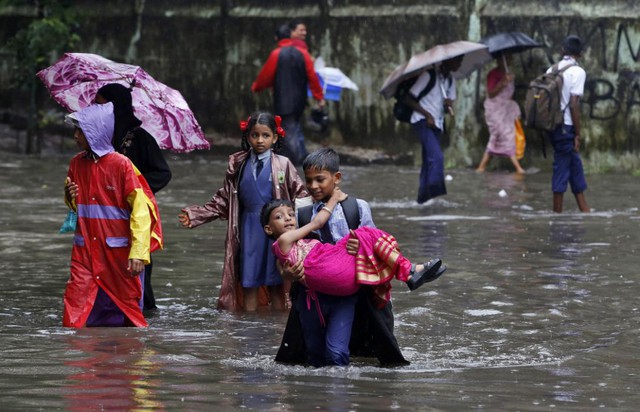 Cậu bé bế em gái qua một đường phố ngập nước sau một cơn mưa ở Mumbai, Ấn Độ.