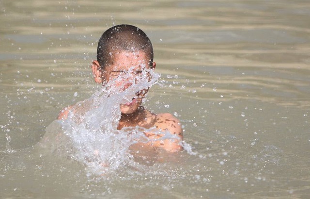 Cậu bé tắm mát dưới dòng kênh trong một ngày nắng nóng tại Kabul, Afghanistan.