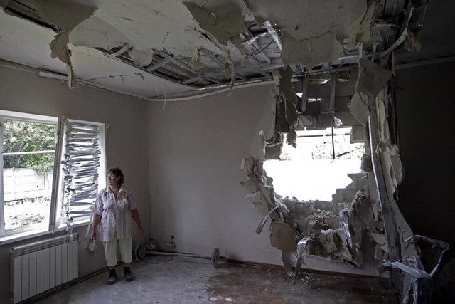 Người dân đứng trong căn nhà bị phá hủy trong đợt pháo kích mới đây ở ngoại ô vùng Donetsk, Ukraine.