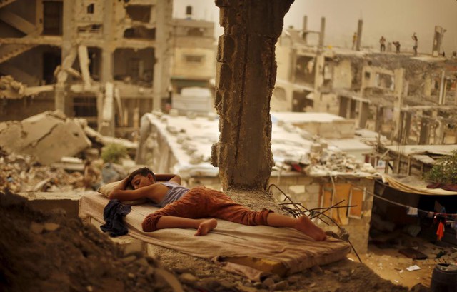 Cậu bé người Palestine ngủ trên tấm nệm giữa ngôi nhà đổ nát của gia đình mình ở thành phố Gaza.