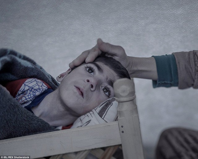 
Shiraz, 9 tuổi, nằm ngủ trên một chiếc nôi trong trại tị nạn ở Suruc, Thổ Nhĩ Kỳ. Cậu bé bị mắc bệnh máu trắng nhưng gia đình không đủ tiền để chữa trị cho cậu.
