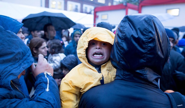 Em bé di cư khóc vì lạnh khi chờ đăng ký tị nạn dười trời mưa rét ỏ Berlin, Đức.