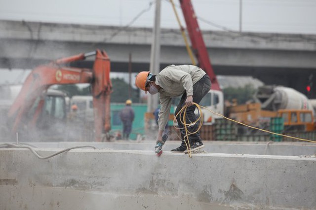 
Phía tường bao của hầm chui, một số công nhân đang dùng máy để mài cho bề mặt bê tông bằng phẳng và lắp lan can.
