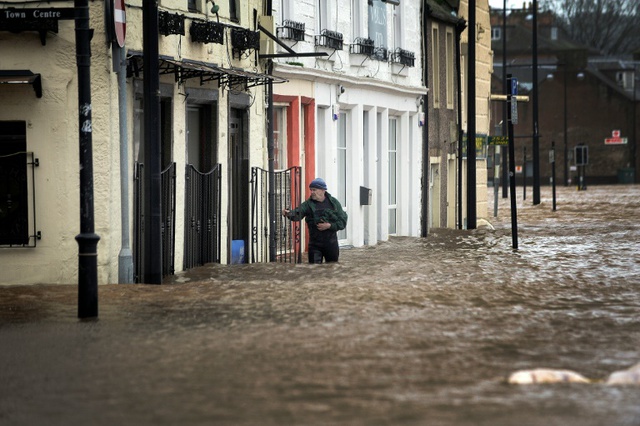 Một người đàn ông lội qua dòng nước lũ trên một đường phố ở Dumfries, miền nam Scotland.