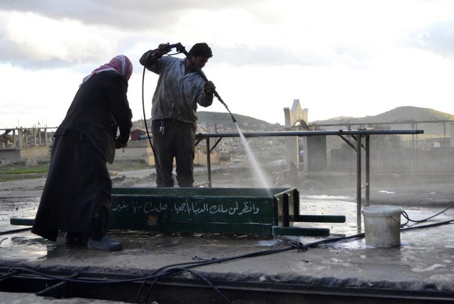 Những người đàn ông rửa máu dính trên 	một chiếc quan tài trên đường phố ở Jabal al-Zawiya, Syria.