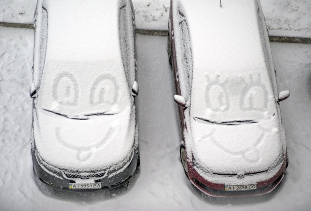 Mặt cười được vẽ trên tuyết bao phủ kín kính chắn gió của ô tô đỗ trước một tòa nhà chung cư ở Kiev, Ukraine.