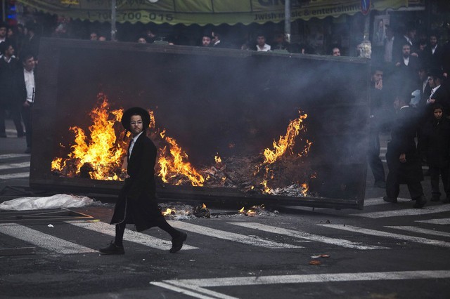 Cậu bé Do Thái Chính thống đi qua đám cháy trong một cuộc biểu tình tại khu phố Mea Shearim, Jerusalem, Israel.