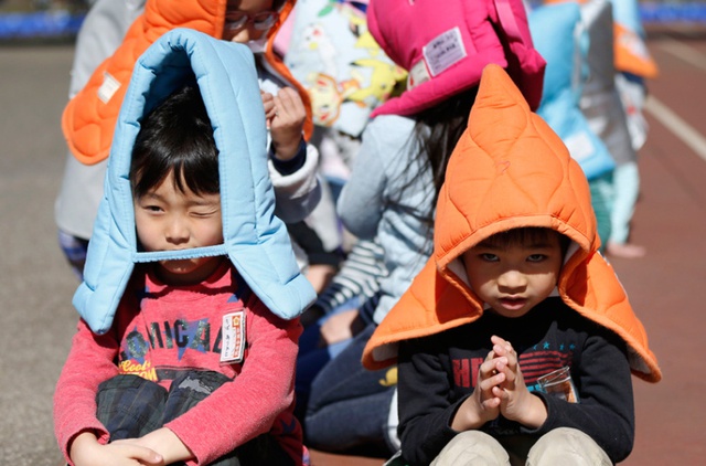 Học sinh đội mũ độn bông để bảo vệ khỏi các vật thể rơi trong một cuộc diễn tập chống động đất tại một trường Tiểu học ở Nhật Bản.