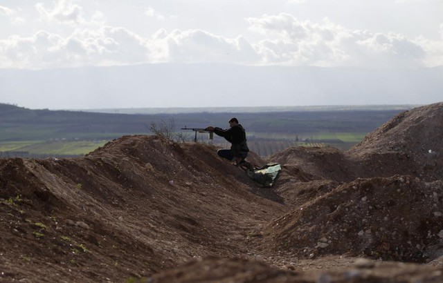 Chiến binh phiến quân Syria chĩa súng nhằm về phía quân đội chính phủ ở ngoại ô thành phố.