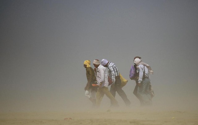Mọi người đi trong bão cát trên bờ sông Hằng tại thành phố Allahabad, Ấn Độ.