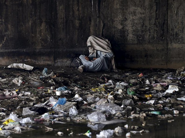 Một người nghiện ma túy che mặt ngồi dùng ma túy dưới cầu ở Kabul, Afghanistan.