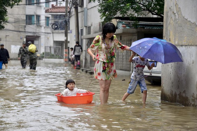 Người phụ nữ cùng con di chuyển trên đường phố ngập lụt tại thành phố Thường Châu, Trung Quốc.