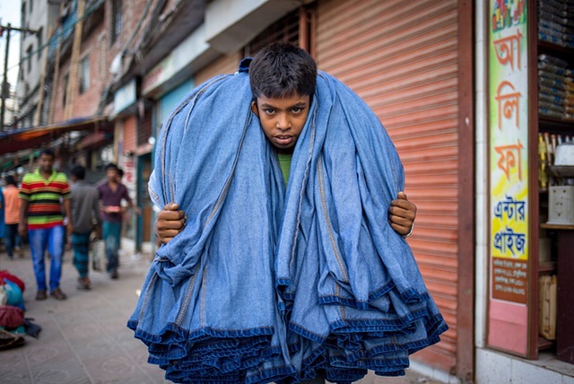 Cậu bé chuyển quần jean cho khách hàng ở Dhaka, Bangladesh.