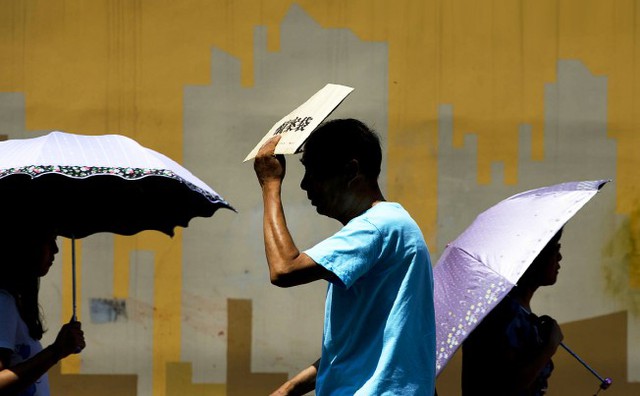 Người đàn ông dùng bì thư để che nắng khi đi dưới trời nóng hơn 40 độ C ở thành phố Bắc Kinh, Trung Quốc.