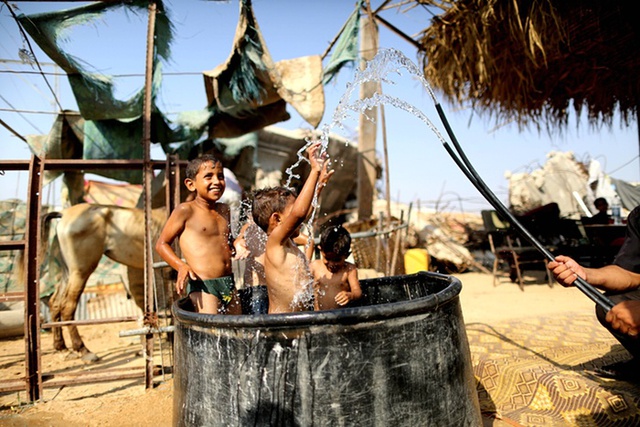 Trẻ em Palestine tắm trong thùng nhựa để tránh nóng tại Beit Hanoun, Gaza.