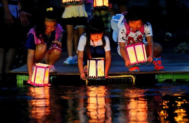 Những em nhỏ thả đèn hoa đăng trên sông ở Gunma, Nhật Bản, để cầu nguyện cho các nạn nhân của vụ tai nạn máy bay số hiệu JAL123 của Japan Airlines 30 năm trước.