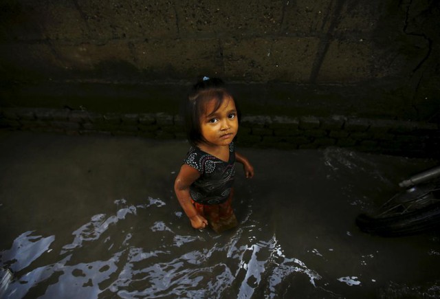 Bé gái đi qua con ngõ nhỏ ngập nước sau mưa lớn tại một khu ổ chuột ở Kathmandu, Nepal.