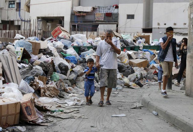 Người dân bịt mũi khi đi qua rác được chất đống dọc đường phố ở Beirut, Li Băng.