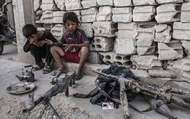 Trẻ em nhìn những khẩu súng thu giữ được nhóm phiến quân Nhà nước Hồi giáo (IS) ở Kobane, Syria.