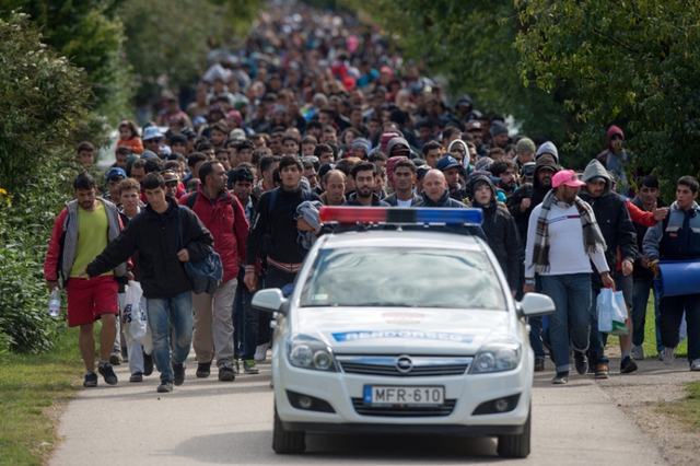 Dòng người di cư đi theo sau ô tô cảnh sát tại thị trấn Hegyeshalom, Hungaria, giáp biên giới với Áo.