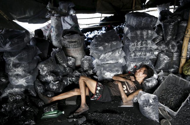 Công nhân nằm nghỉ ngay cạnh những túi than hoa tại một cửa hàng ở Manila, Philippines.