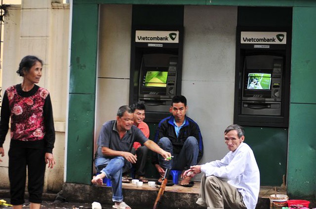 
Những người dân lao động ngồi trong một cây ATM trên đường Chu Văn An (Ba Đình), uống trà nóng và hút thuốc lào để tránh rét.
