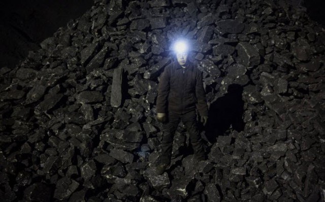 
Công nhân đứng trên đống than đá trong ca làm việc ban đêm.
