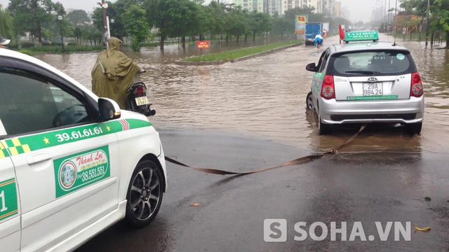 Hai xe taxi kéo nhau đi qua chỗ ngập.