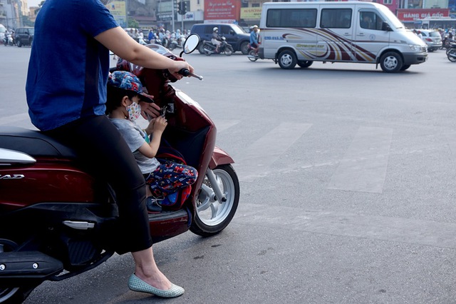 Trẻ được chở bằng cách đứng, ngồi ở chỗ để chân rất phổ biến. (Ảnh chụp trên phố Xã Đàn).