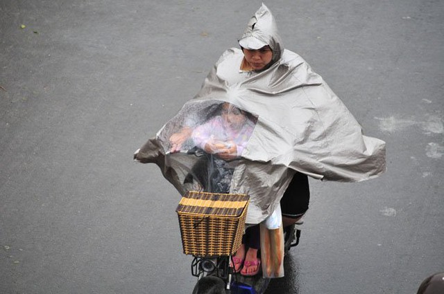
Một em nhỏ trú dưới áo mưa của mẹ trên đường Yên Phụ (Tây Hồ, Hà Nội).
