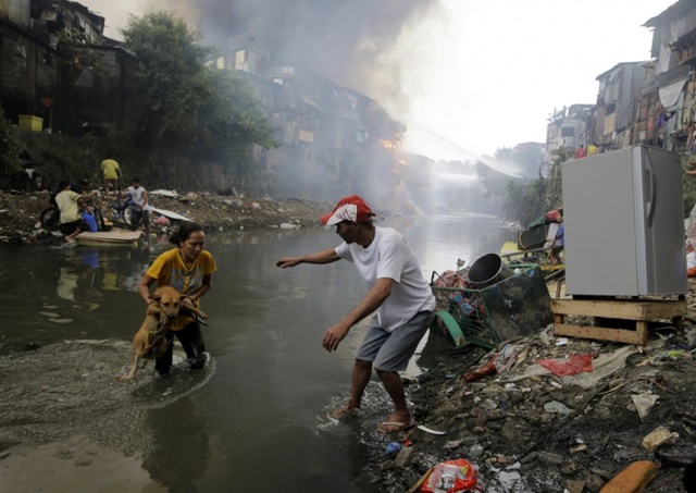 Người dân cứu chó và đồ đạc khi hỏa hoạn thiêu rụi hàng trăm ngôi nhà tại một khu ổ chuột ở thành phố Quezon, Philippines.
