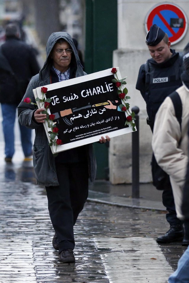 Một người đàn ông cầm tấm biển ghi dòng chữ Je suis Charlie (Tôi là Charlie), lặng lẽ rời khỏi nghĩa trang Montparnasse.